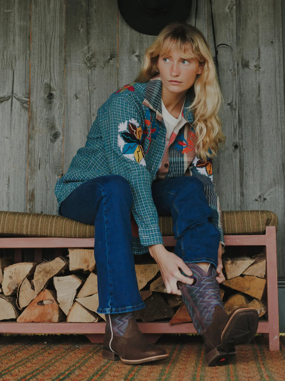 A woman sat down putting on a pair of Durango western boots.