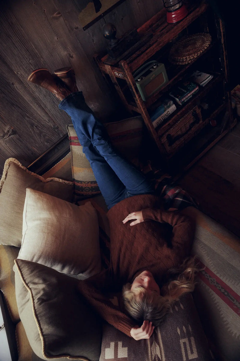 Jenna lying on a couch with feet up in a cosy room.