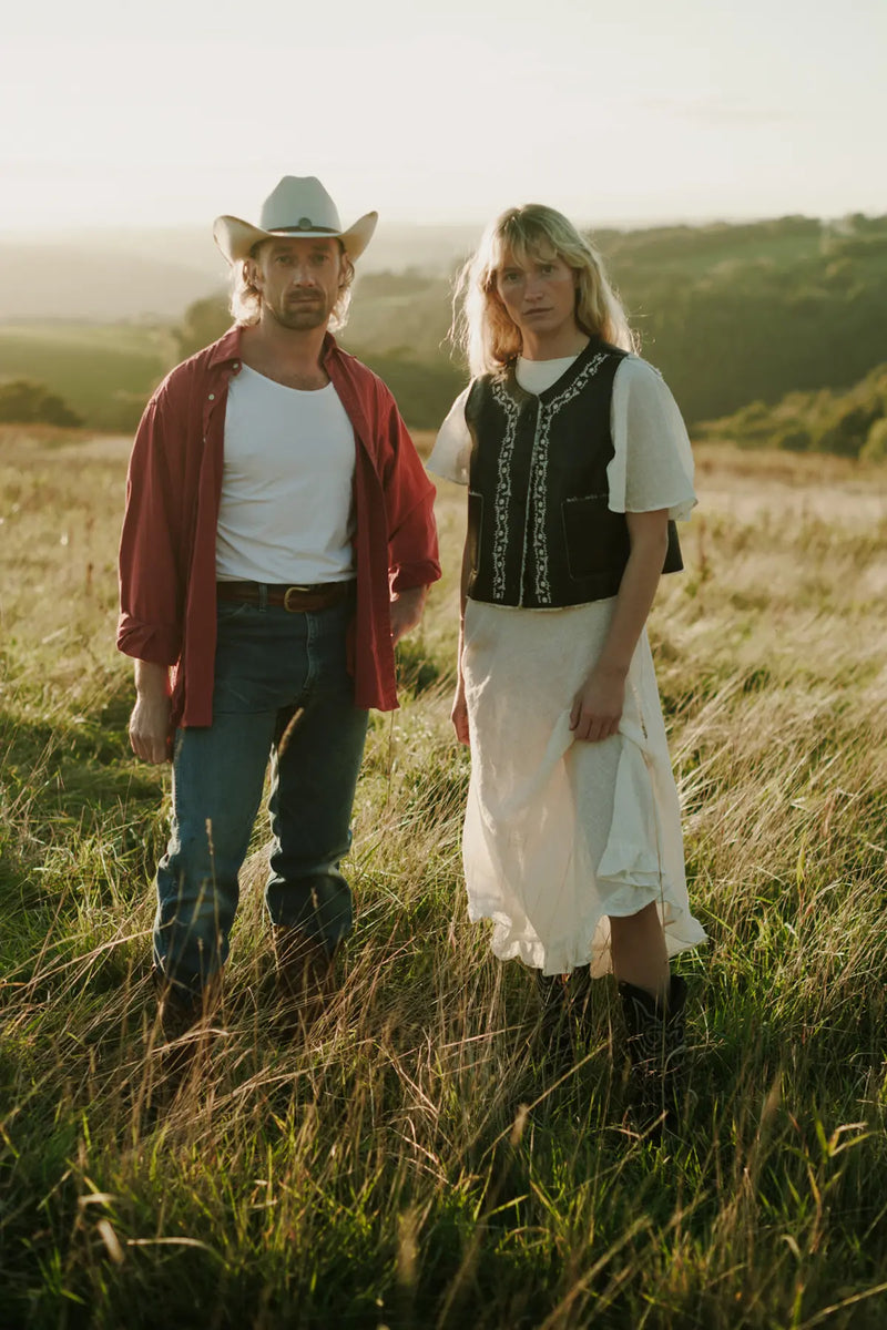 Matthew and Jenna standing in a field with a scenic background.