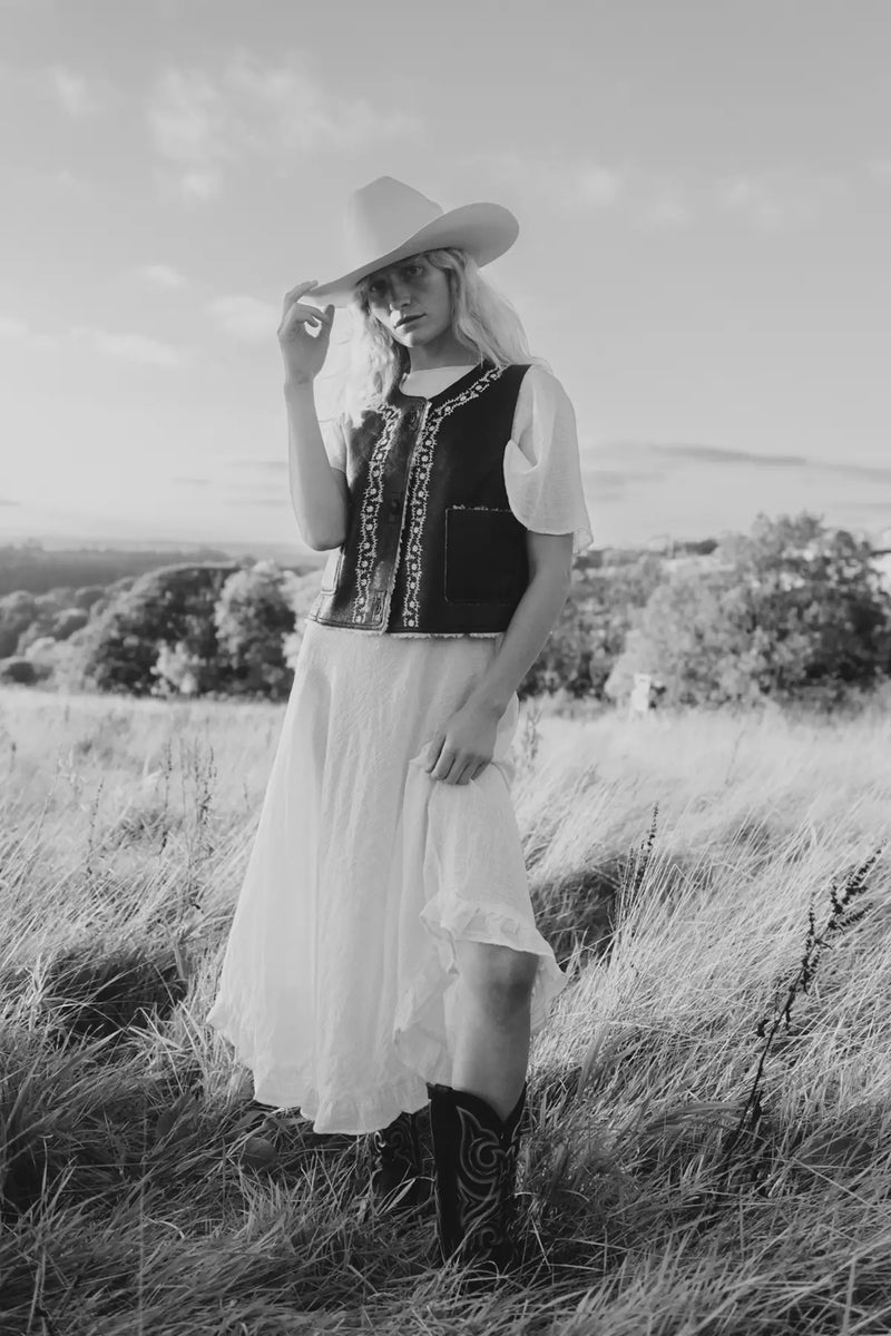 Jenna in a cowboy outfit, wearing Durango boots while stood in a field.