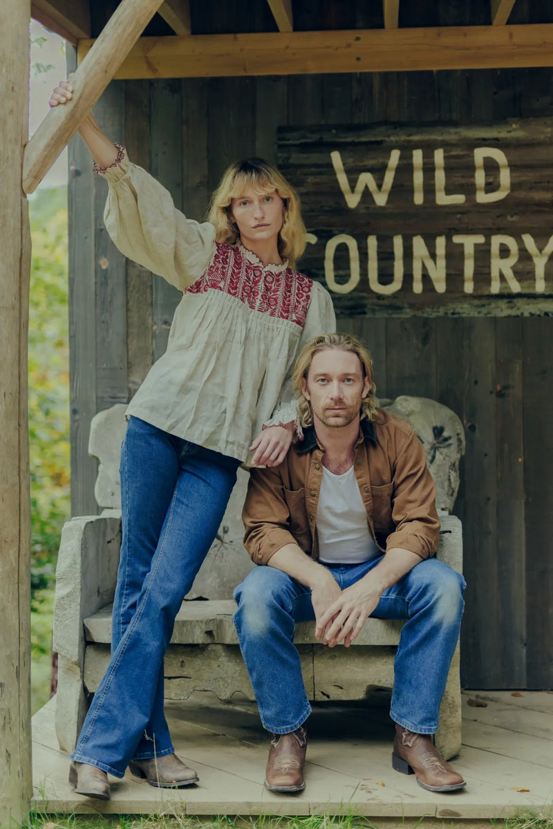 Jenna and Matthew sitting on a wooden bench with 'Wild Country' sign in the background.